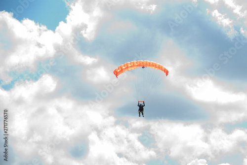 Skydivers is flying in the blue sky against the background of clouds.