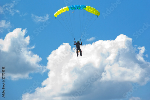 Skydivers is flying in the blue sky against the background of clouds.