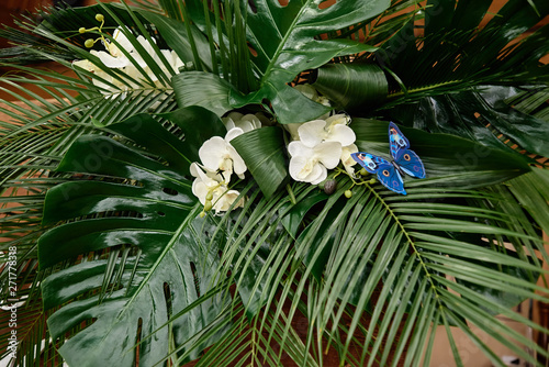 Fototapeta Naklejka Na Ścianę i Meble -  Lush floral arrangement of orchids and monstera leaves on wedding table. Wedding presidium in restaurant, copy space. Banquet table for newlyweds. Luxury wedding decor