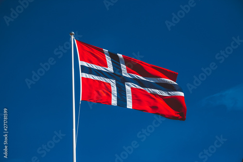 Norwegian flag against the blue sky. The wind blows against the blue sky without clouds
