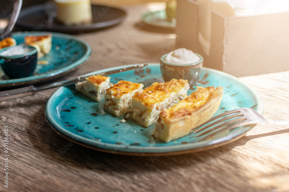 Chicken Quiche with mushrooms Recipe. Quiche Lorraine with chicken and Champignons and sauce on a blue plate on wooden table. Pie with chicken and mushrooms. Traditional French food Chicken Quiche with mushrooms Recipe. Quiche Lorraine with chicken and Champignons and sauce on a blue plate on wooden table. Pie with chicken and mushrooms. Traditional French food