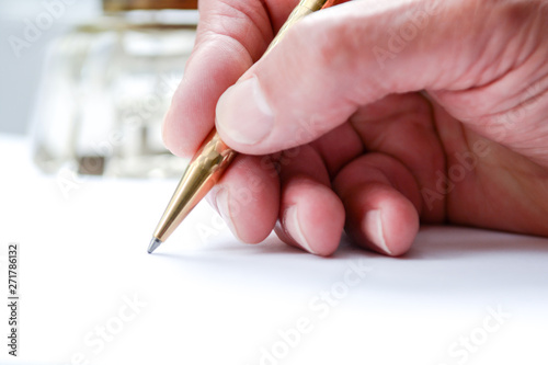 Man writing with pen on paper, close up of hand hollding pen to write on paper document