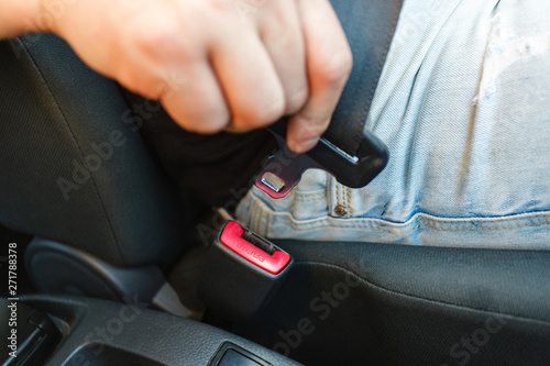 Close-up of car seat belt fastener. Men s hand fastens the seat belt of the car. Close your car seat belt while sitting inside the car before driving and take a safe journey.