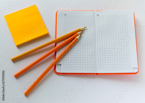 .orange notebook lies on the table next to an orange pencil and sticker © ValDan