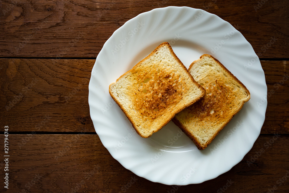 Plate with toasted bread isolated on wooden background, top view