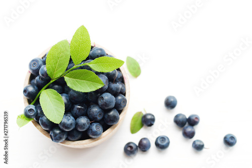 Slika na platnu Fresh bilberry in a wooden bowl on a white background, top view