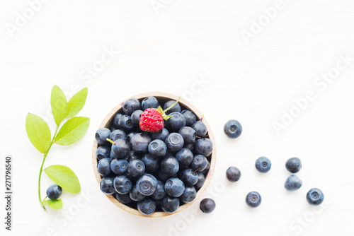 Fotografija Fresh bilberry in a wooden bowl on a white background, top view