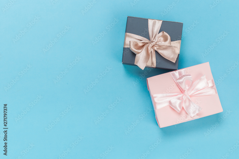 beautiful gift boxes wrapped in paper with gold and pink ribbon on a blue surface. Top view beautiful gift boxes wrapped in paper with gold and pink ribbon on a blue surface. Top view