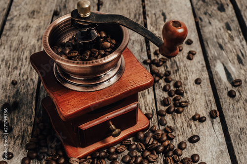 Hand coffee grinder with coffee beans on wooden background.