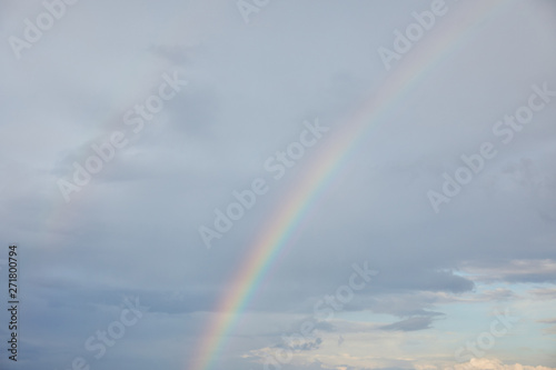 rainbow on blue sky background with clouds and sunlight © LIGHTFIELD STUDIOS