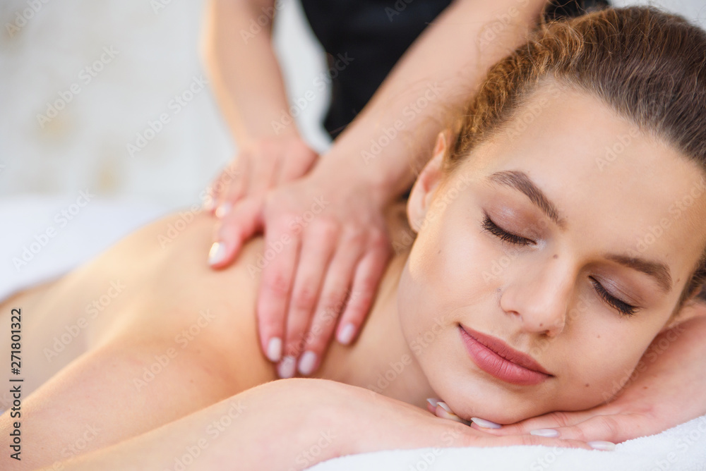 Handsome relaxing woman during massage in spa salon.