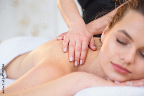 Young female masseur making massage in spa salon.