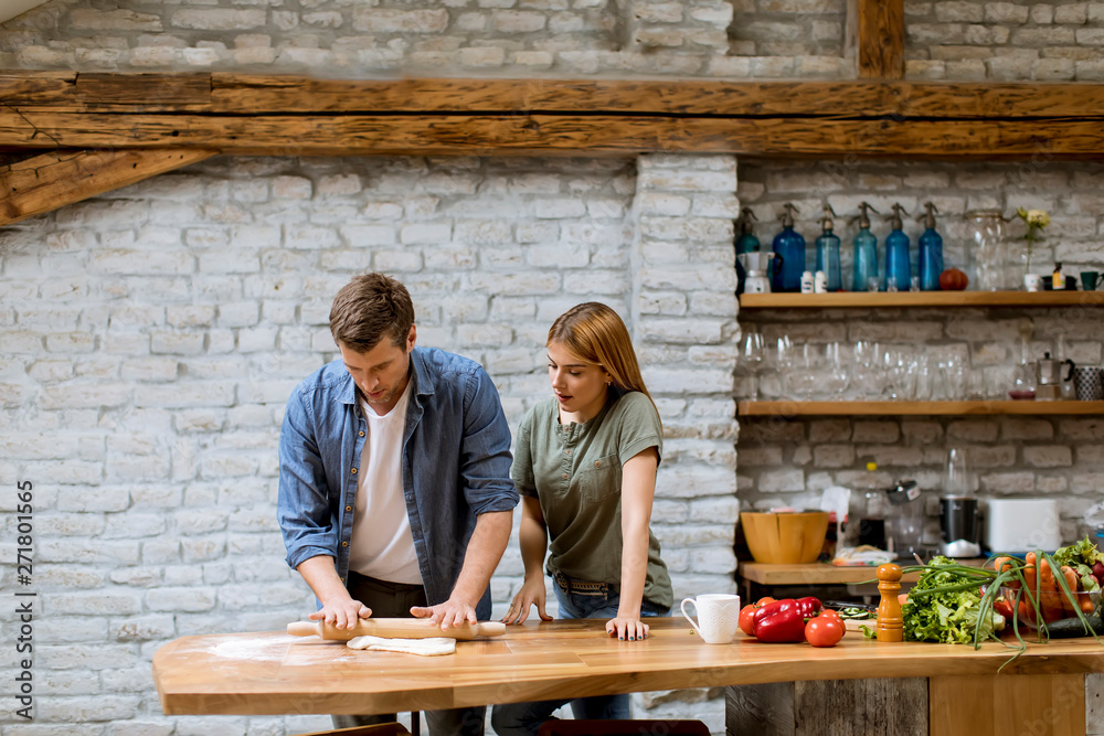 Young couple caking pizza in kitchen together