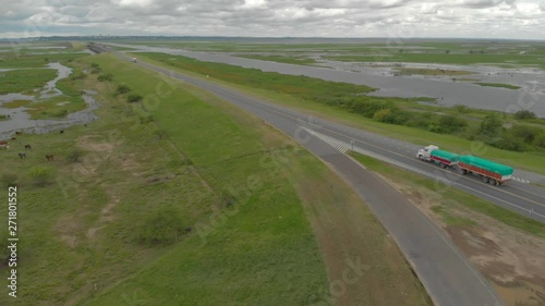 Wide, aerial shot of trucks and cars driving through the road in the middle of beautiful rivers in Entre Rios, province of Argentina. photo