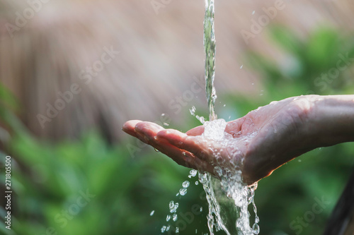 closeup water flow to hand of women for nature concept on the garden background.