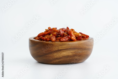 Dried bird's eye chili peppers in a wooden bowl. White background, high resolution