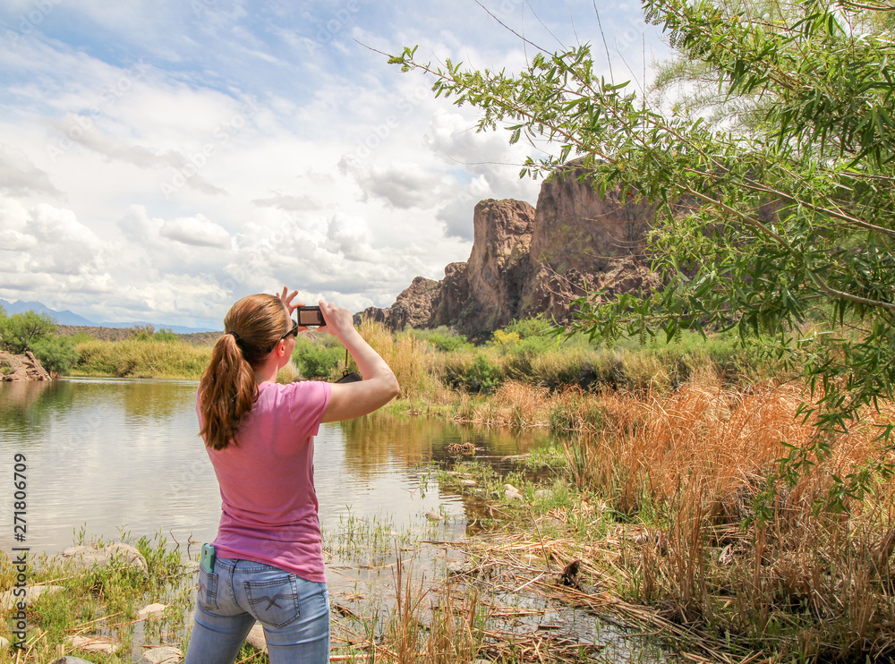 A young woman takes a picture of beautiful Arizona desert scenery and mountains