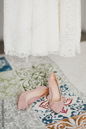 Bridal fashion. Pink shoes and wedding dress in the bedroom.