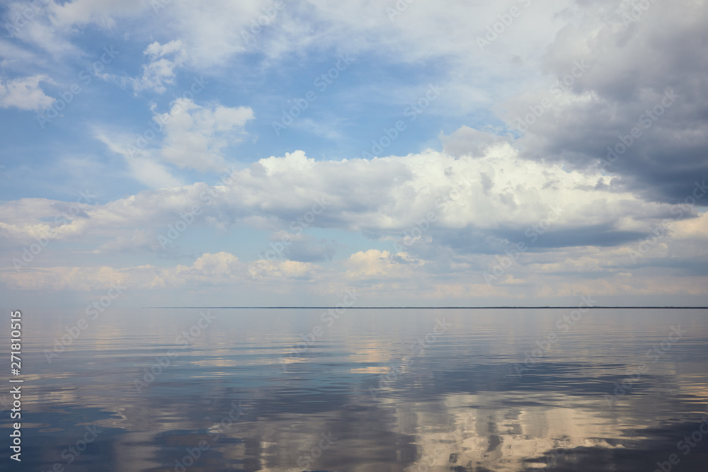 Obraz premium Calm pond and light blue sky with white clouds