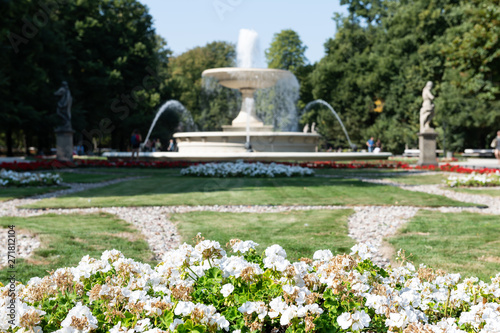 Warsaw, Poland tourists by water fountain in summer Saxon Gardens Park with spraying splashing sculptures and flower bed