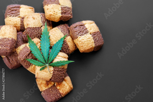 Breakfast with sweet cookies on a dark background with a green leaf of cannabis. Marijuana CBD dessert. Copy space. View from above. Concept of marijuana use for medicinal purposes