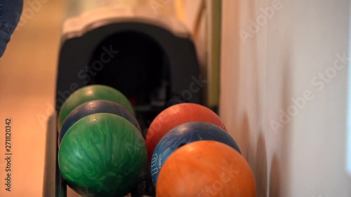 In the frame of the Ball return system, a girl in blue jeans takes out a green ball and walks away,close-up
