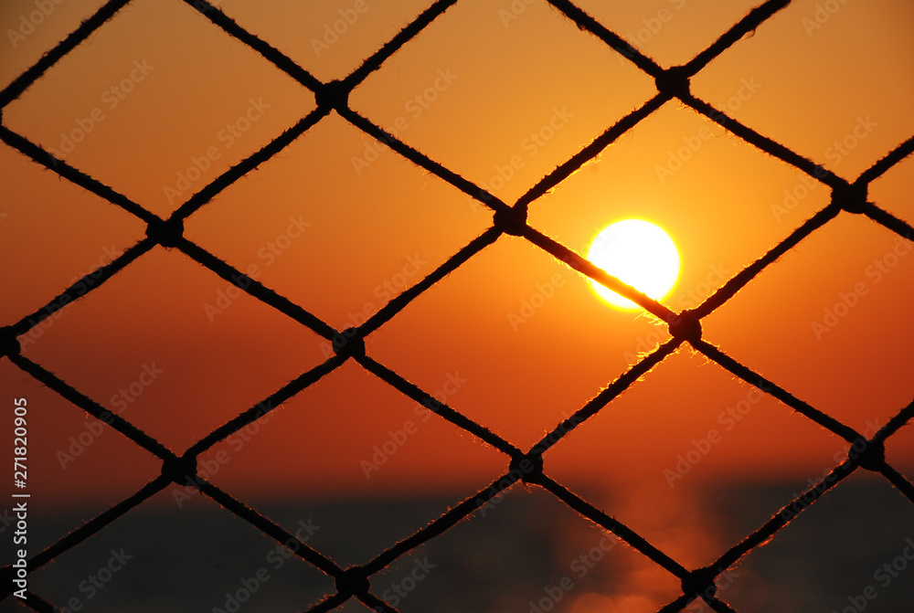 Fototapeta premium View of the sunset through the net of sailboat.