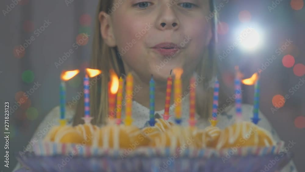 Teen girl blows out candles on cake cakes on her birthday.