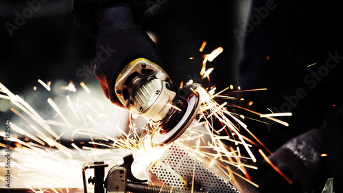 close up of a grinder machine cutting steel with metal sparks and dark black copy space background. photo