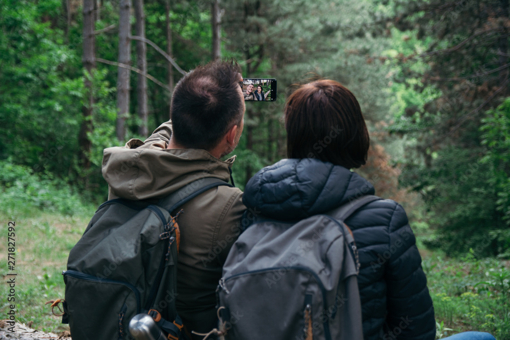 Young couple using smart phone in the forest. Taking picture Young couple using smart phone in the forest. Taking picture