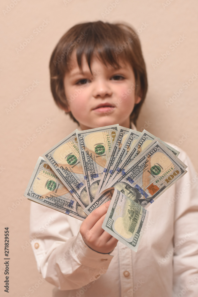 Happy child with money dollar, little businessman. Pile of United States dollar hundred USD banknotes in boy's hand. Happy child with money dollar, little businessman. Pile of United States dollar hundred USD banknotes in boy's hand.