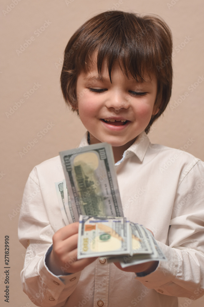 Happy child with money dollar, little businessman. Pile of United States dollar hundred USD banknotes in boy's hand. Happy child with money dollar, little businessman. Pile of United States dollar hundred USD banknotes in boy's hand.