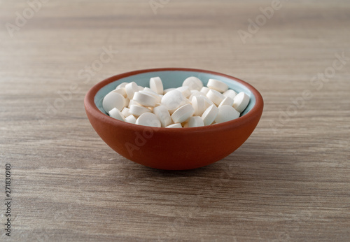 DHEA pills in a bowl on a table side view