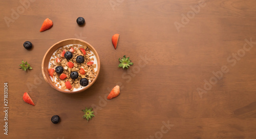 Fresh corn flakes cereal and fruits strawberry and blueberry in wood bowl  Copy space on the right