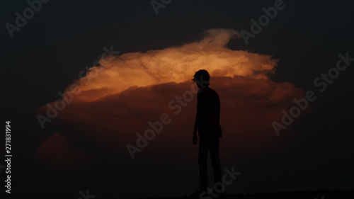 Silhouette of man standing in front of dramatic orange sky during sunset
