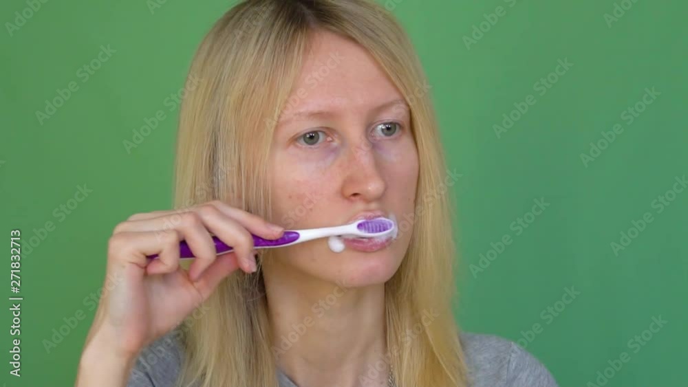 Beautiful woman brushing her teeth and smiling - oral hygiene - Videotape against the background of a colored key. Green background, hrome. Beautiful woman brushing her teeth and smiling - oral hygiene - Videotape against the background of a colored key. Green background, hrome.