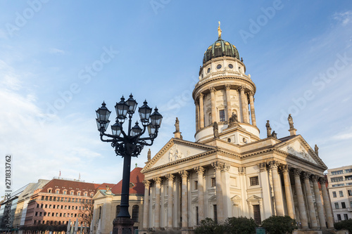 Old streetlight and Französischer Dom (French Cathedral) at the Gendarmenmarkt Square in Berlin, Germany, on a sunny morning.