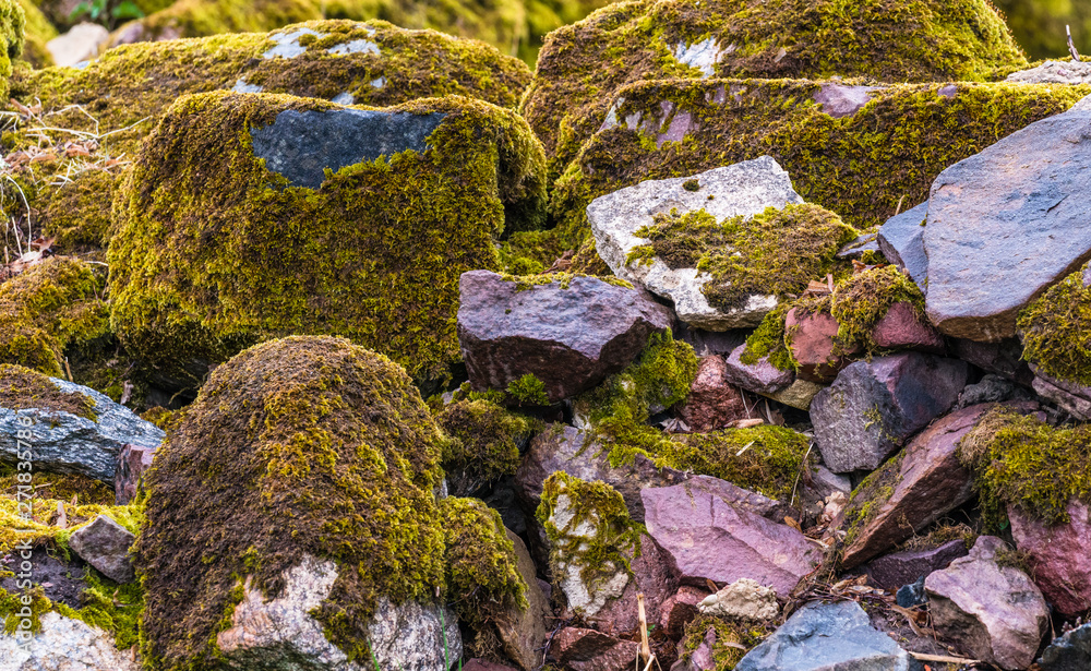 various brown and mottled boulders close up, stacked, some of them overgrown with moss and grass various brown and mottled boulders close up, stacked, some of them overgrown with moss and grass