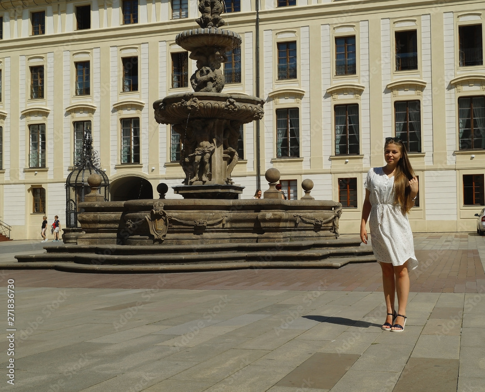 Young girl student posing by the fountain on a sunny day in Prague Castle in Prague