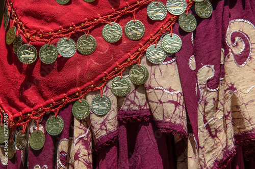 Background of draped gypsy shawls with decorative coin and bead fringe and distinctive weave for each piece - red and burgundy colors with a batik and embroidery edge on one - boho belly dancing