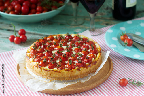 Tart, pie or cheesecake with cottage cheese and tomatoes, served with red wine on a wooden background.