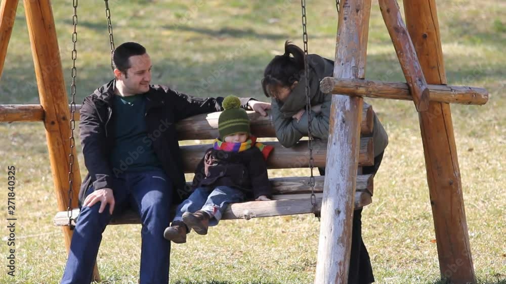 Mother push swing with father and son, spare time in nature Mother push swing with father and son, spare time in nature
