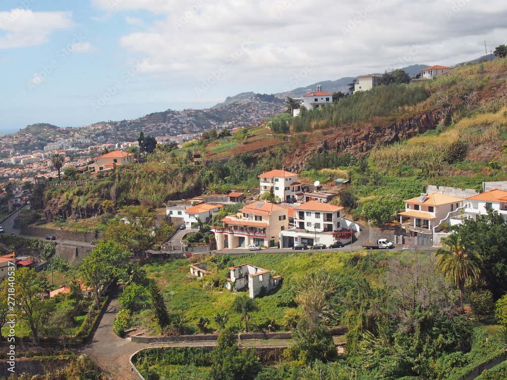 an aerial view of funchal in madeira with houses and farms on a mountainside with the city and coast in the distance