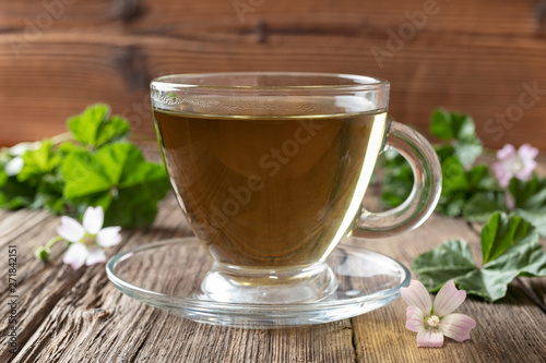 A cup of mallow tea with fresh dwarf mallow plant