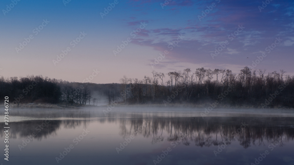Sunrise lake and sky mirrored images, Calm as glass lake water reflecting the sky above, misty water