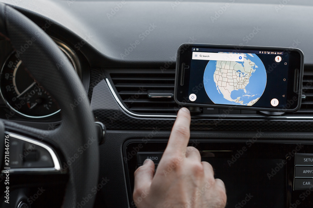 Close up to male driving and using navigation on the smartphone screen. Choose direction, globe on the screen.