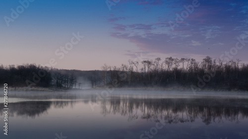 Sunrise lake and sky mirrored images, Calm as glass lake water reflecting the sky above, misty water photo