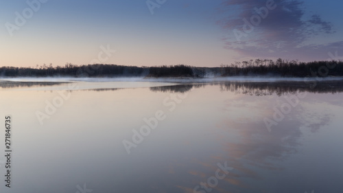 Sunrise lake and sky mirrored images  Calm as glass lake water reflecting the sky above  misty water