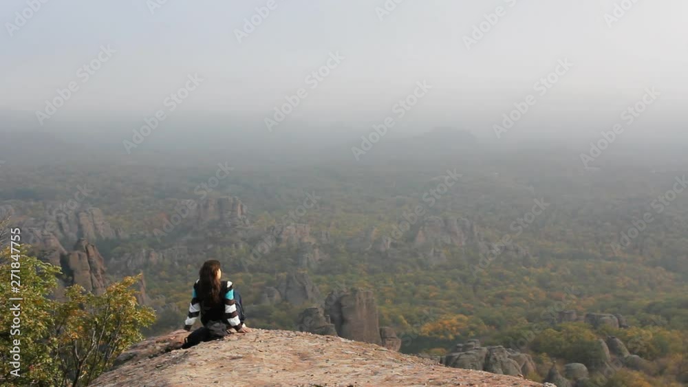 Young woman sits on top of mountain and enjoy the nature panorama Young woman sits on top of mountain and enjoy the nature panorama