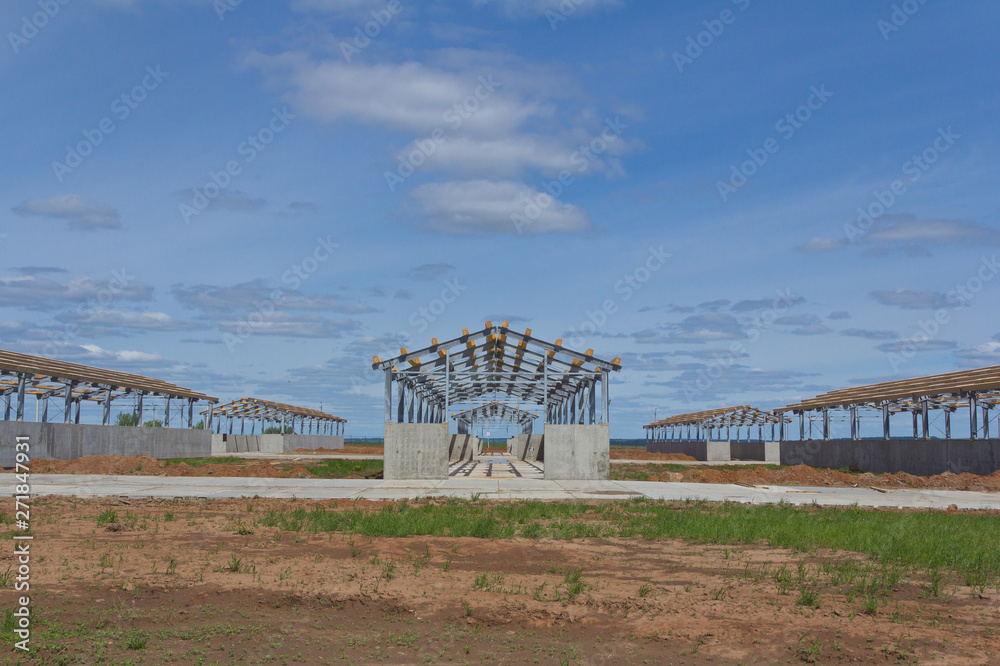 The metal frame of the building on a reinforced concrete base. The use of materials from metal and concrete in modern construction.